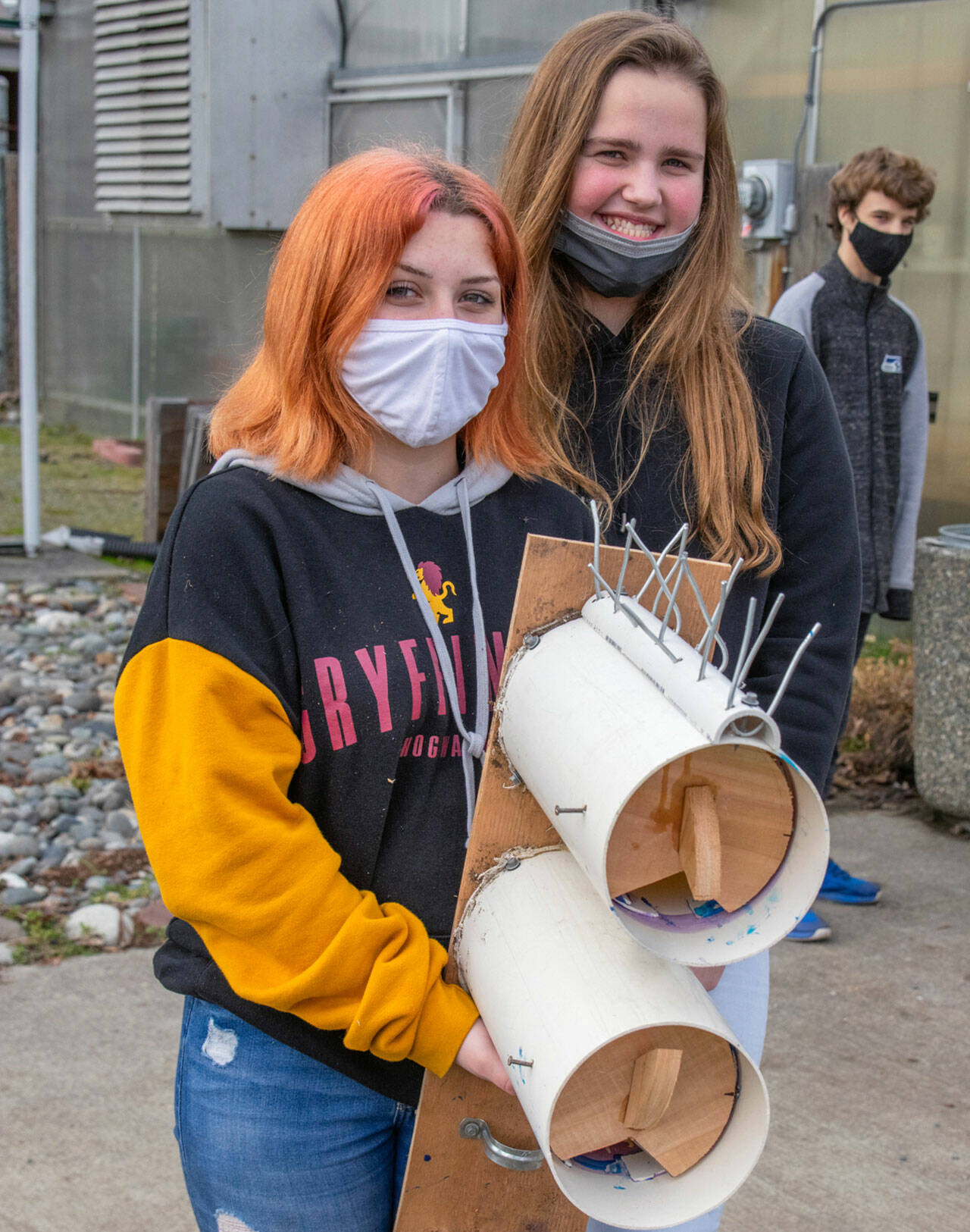 Shasta Larson and Addison Loewen, two of 52 Sequim High School students who built nesting boxes, hold up a finished piece with space for two Purple Martin families. (Emily Matthiessen/Olympic Peninsula News Group)