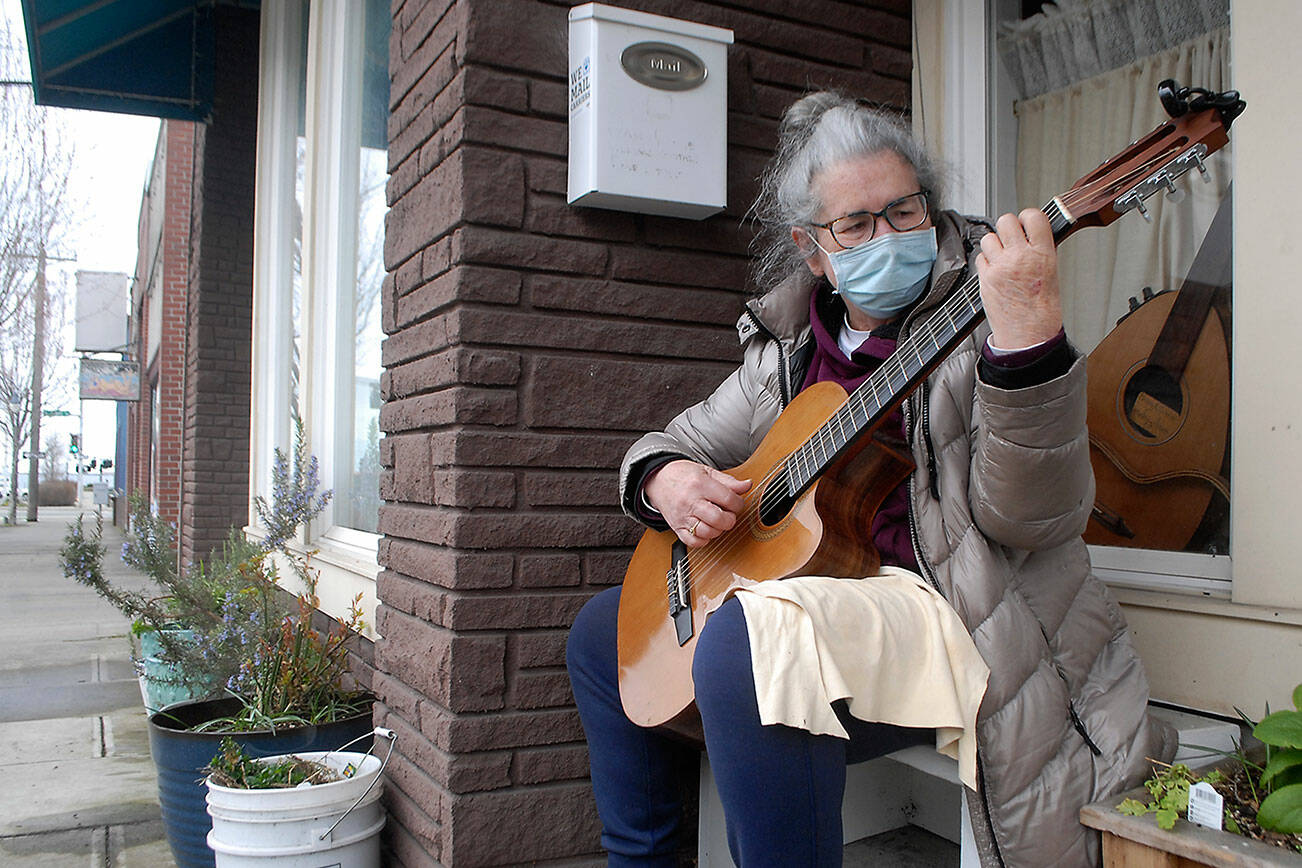 Jan Dove plays a guitar that was custom made for her by her husband, luthier Steve Card of Wildcard Guitars, in front of the guitar workshop, 111 N. Oak St., in downtown Port Angeles. Dove said she wanted a classical style guitar, but with a cutout at the base of the neck, so one was made to order. (Keith Thorpe/Peninsula Daily News)