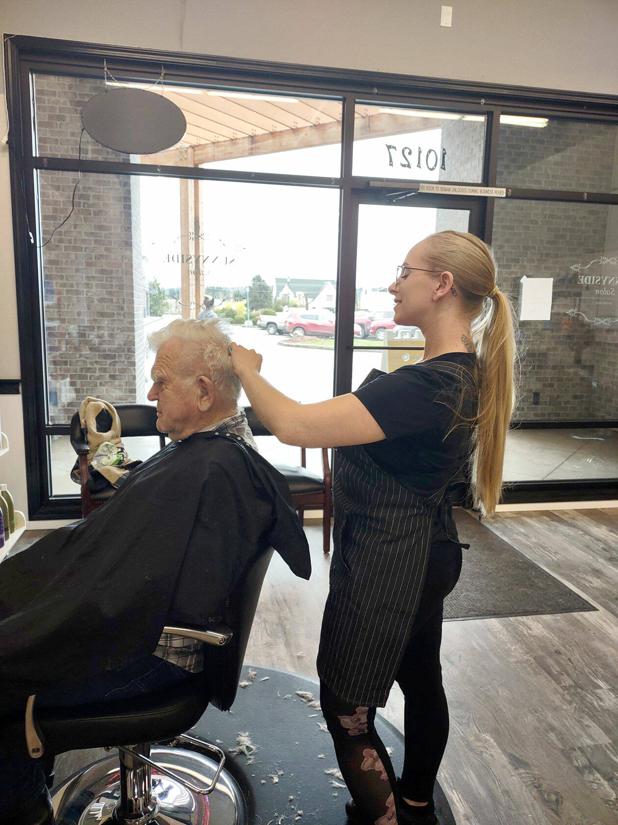 Nikhita Rogers gives her grandfather, Art Rogers, a haircut in her new barbershop.