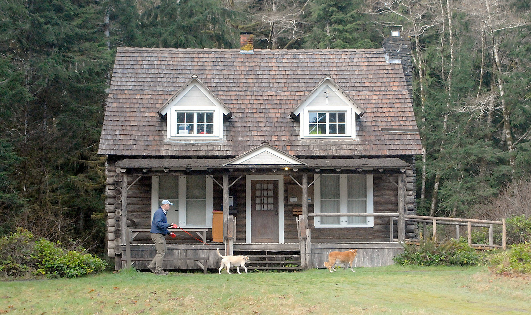 Matthew Carter of Sequim walks his dogs Roxie and Izaak, right, past the Storm King Ranger Station at Barnes Point near the shore of Lake Crescent in Olympic National Park on Saturday. The Barnes Point area is home to the Lake Crescent Lodge, which is open weekends and then daily beginning April 29, as well as the NatureBridge environmental science park and the trailhead to Marymere Falls. (Keith Thorpe/Peninsula Daily News)