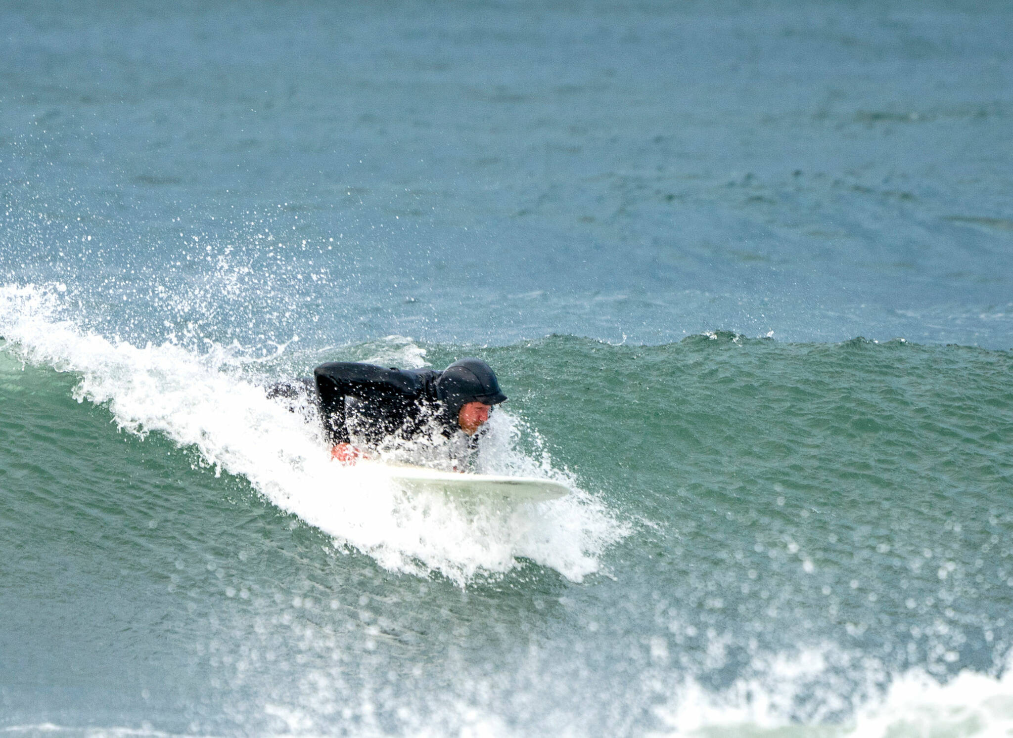 A surfer starts to get up on his board to catch a nice 5-foot wave that was formed by high winds and tide at Port Townsend’s Point Hudson beach on Monday morning. (Steve Mullensky/for Peninsula Daily News)