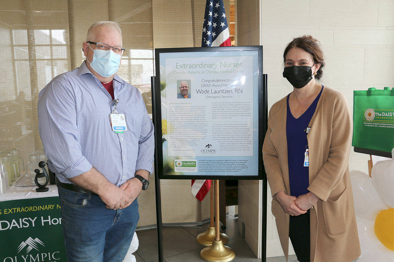 Emergency department nurse Wade Lauritzen, left, receives a DAISY award from Vickie Swanson, Olympic Medical Center’s chief nursing officer.
