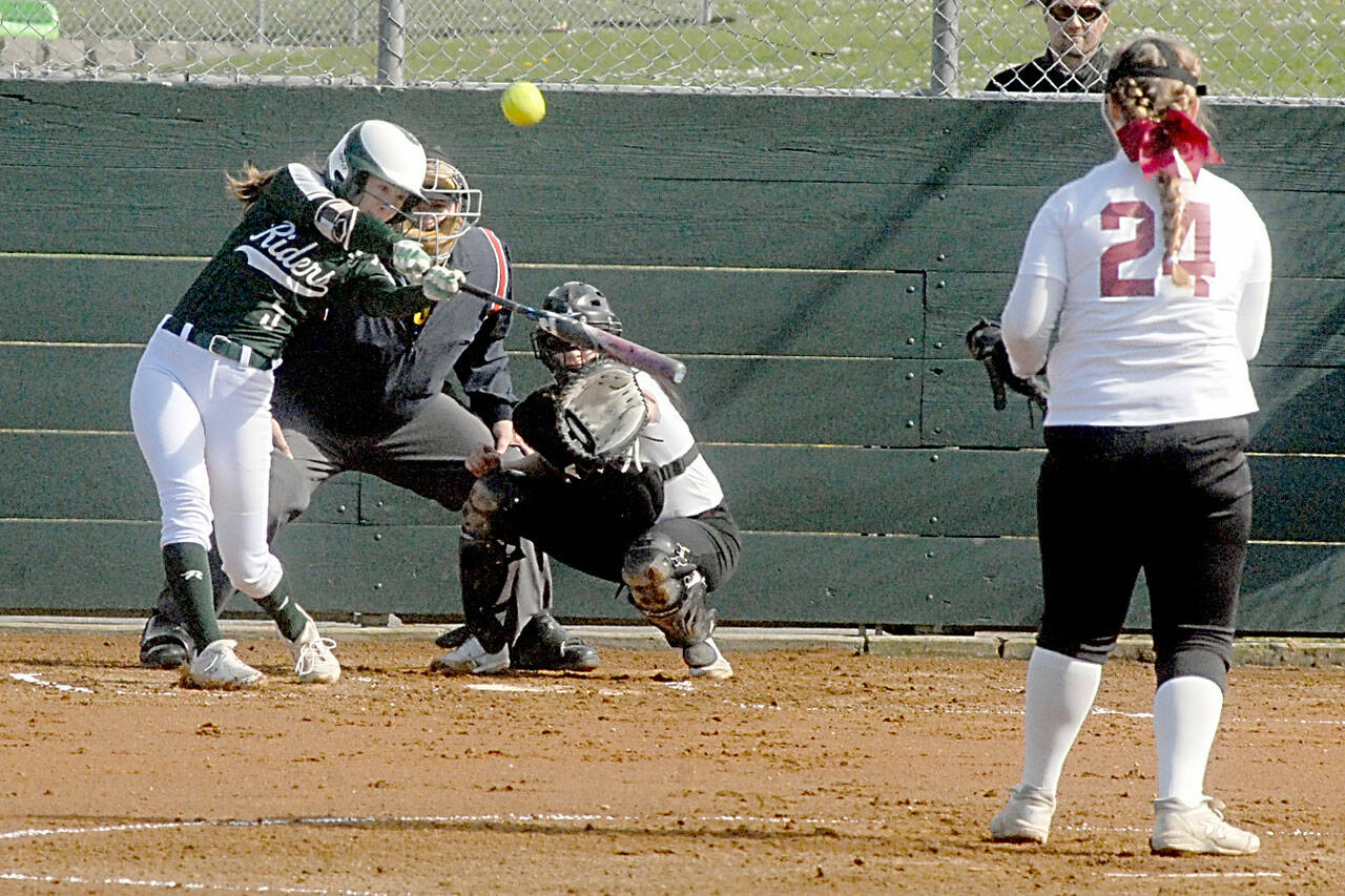 Port Angeles’ Zoe Smithson bats for a home run to lead off the first inning as Kingston catcher Audrey Rienstra watches the delivery from pitcher Kiera Alvarez on Thursday at the Dry Creek Athletic Fields in Port Angeles. Keith Thorpe/Peninsula Daily News