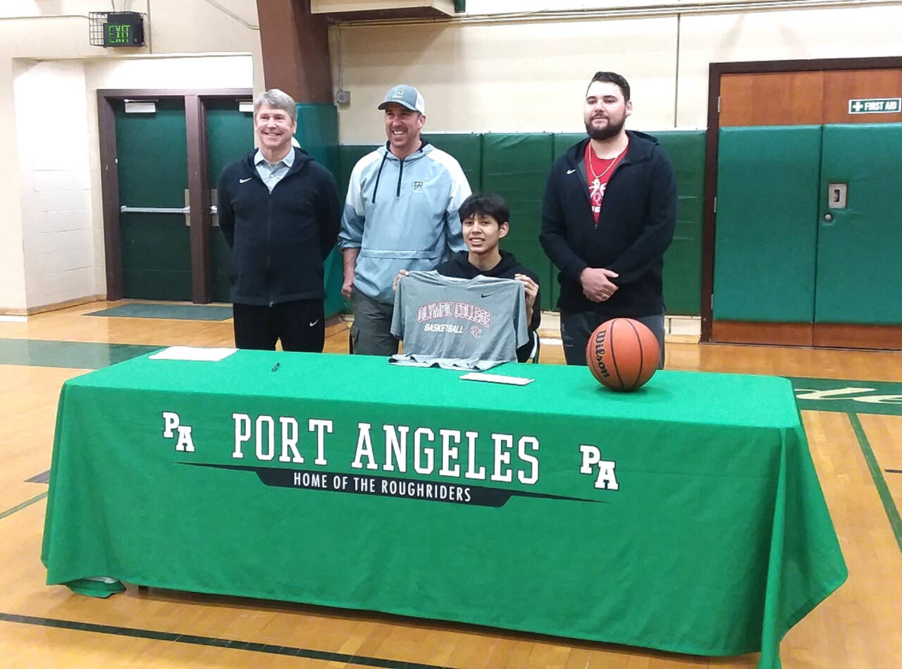 Port Angeles High School basketball player Quanah Wheeler, seated, signs to play for Olympic College last week. Standing from left, are Olympic College men’s assistant coach John Callaghan, Port Angeles boys basketball coach Kasey Ulin and Olympic College men’s coach Ryley Callaghan. (Pierre LaBossiere/Peninsula Daily News)