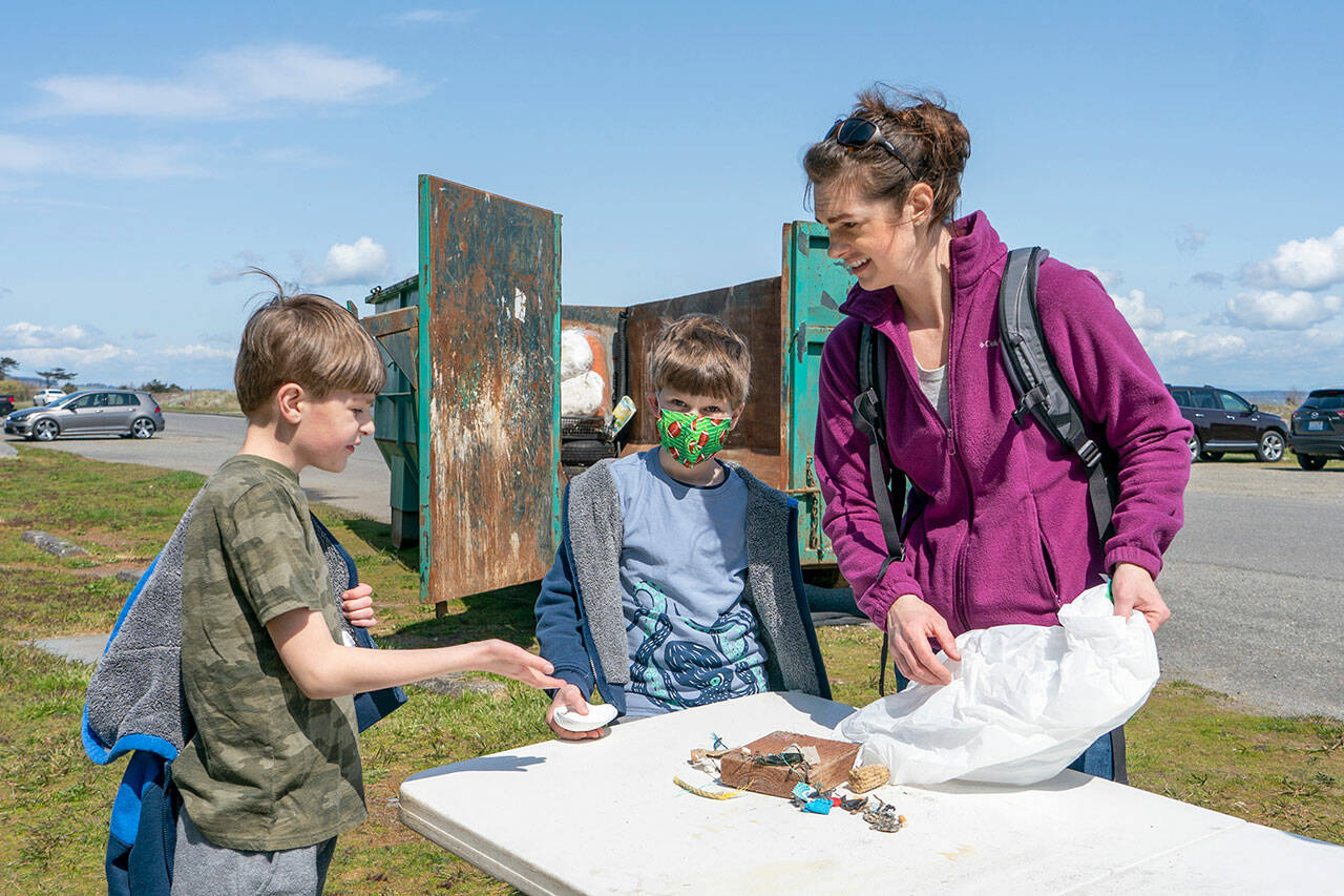 Chelsea Rosenberger, right, and sons Josiah and Micah, go through the bits of trash they picked up along a beach at Fort Worden State Park on Saturday as their volunteer contribution for Earth Day. The family participated in a beach cleanup sponsored by the Marine Science Center in Port Townsend. (Steve Mullensky/for Peninsula Daily News)