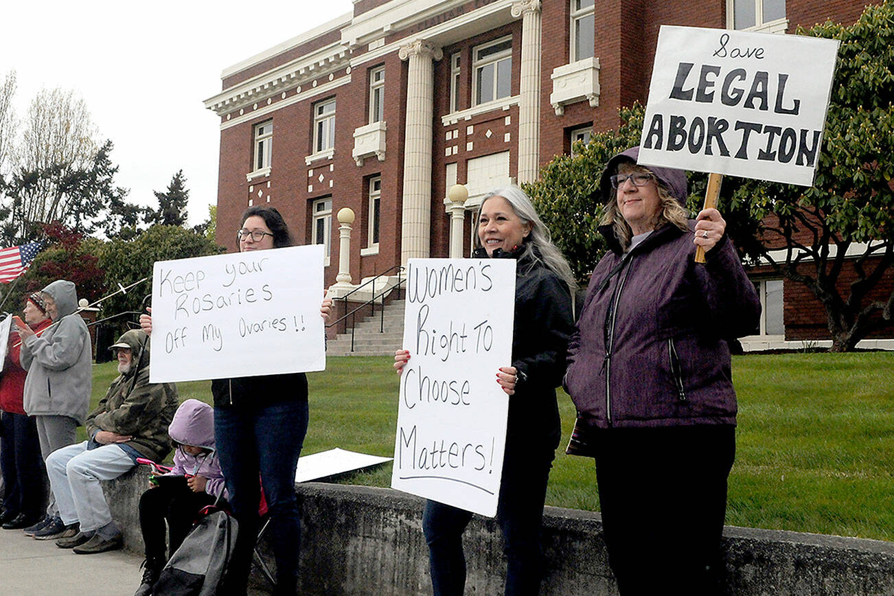 Reproductive rights supporters, from left, Tawny Bagby, Jill Coughenour and Janet Ferris, all of Port Angeles, hold signs protesting the possible overturning of the Roe v. Wade by the U.S. Supreme Court during a gathering on Tuesday in front of the Clallam County Courthouse. About 60 people took part in the event. (Keith Thorpe/Peninsula Daily News)