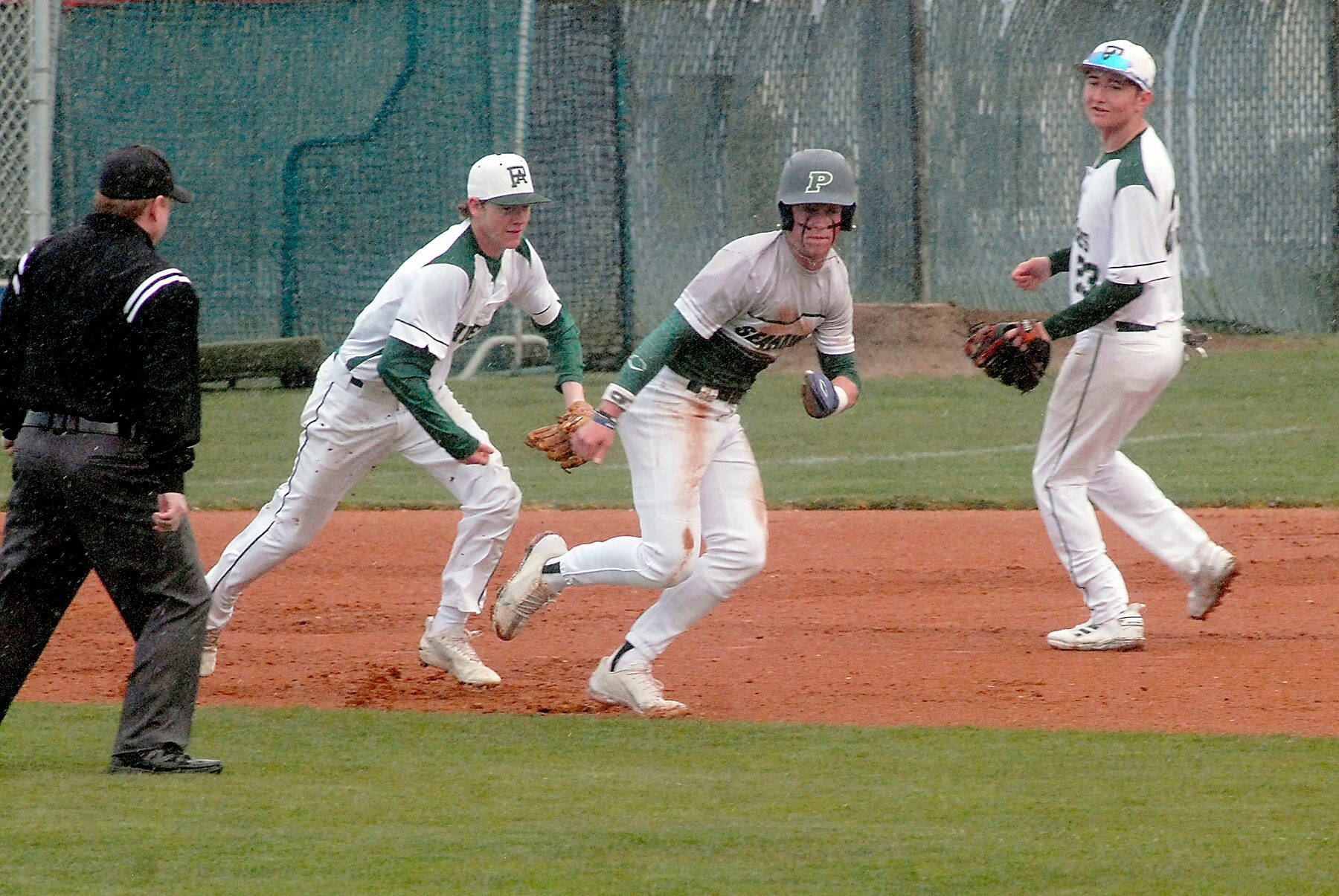 Peninsula baserunner Payton Knowles, center, gets chased by Port Angeles shortstop Michael Soule as second baseman Colton Romero looks on after Knowles was caught in a rundown between second and third and eventually tagged out in the first inning earlier this season at Port Angeles Civic Field. (Keith Thorpe/Peninsula Daily News)