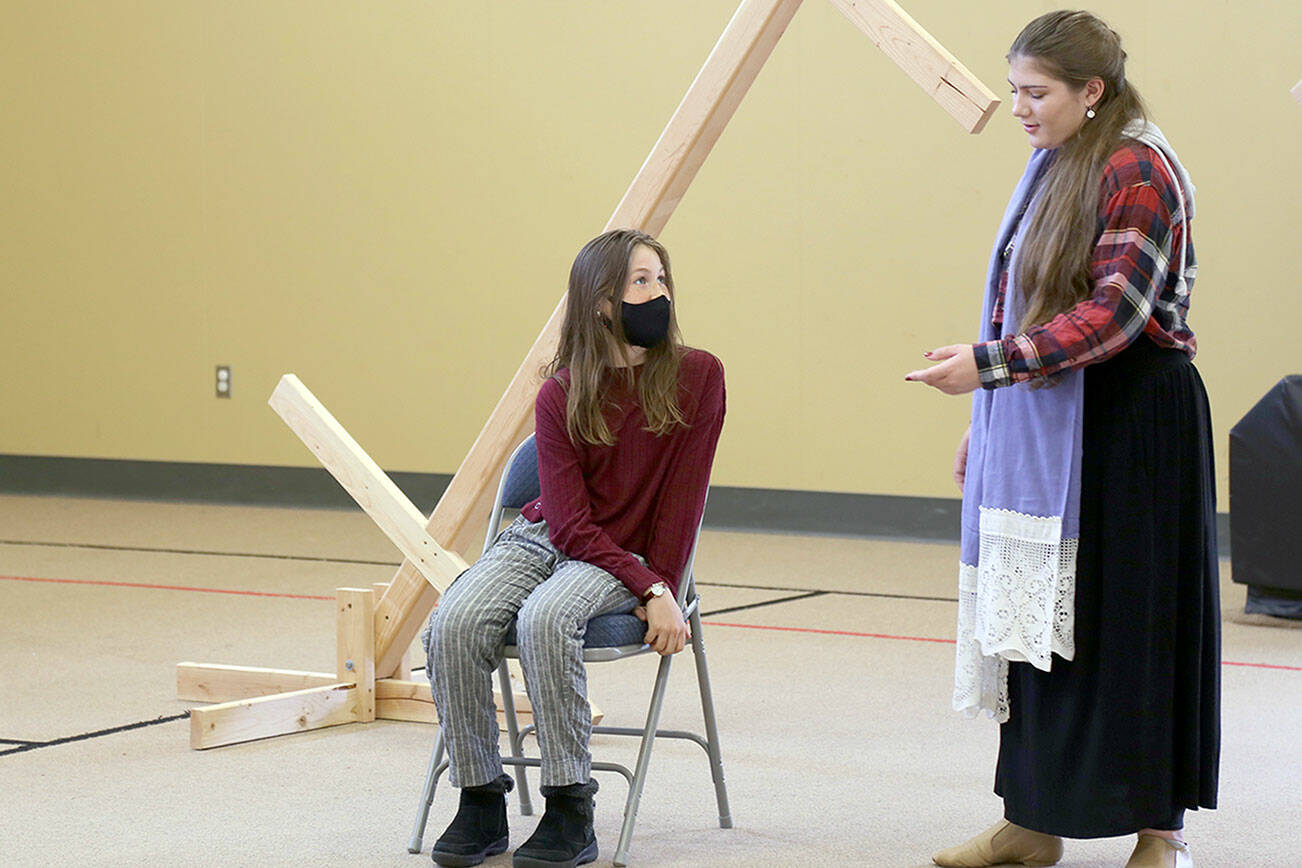 Kaylee R. Klebanow, seated, playing Miranda, looks up at Brianna Palenik, playing Prospera, during rehearsals of 'The Tempest.'