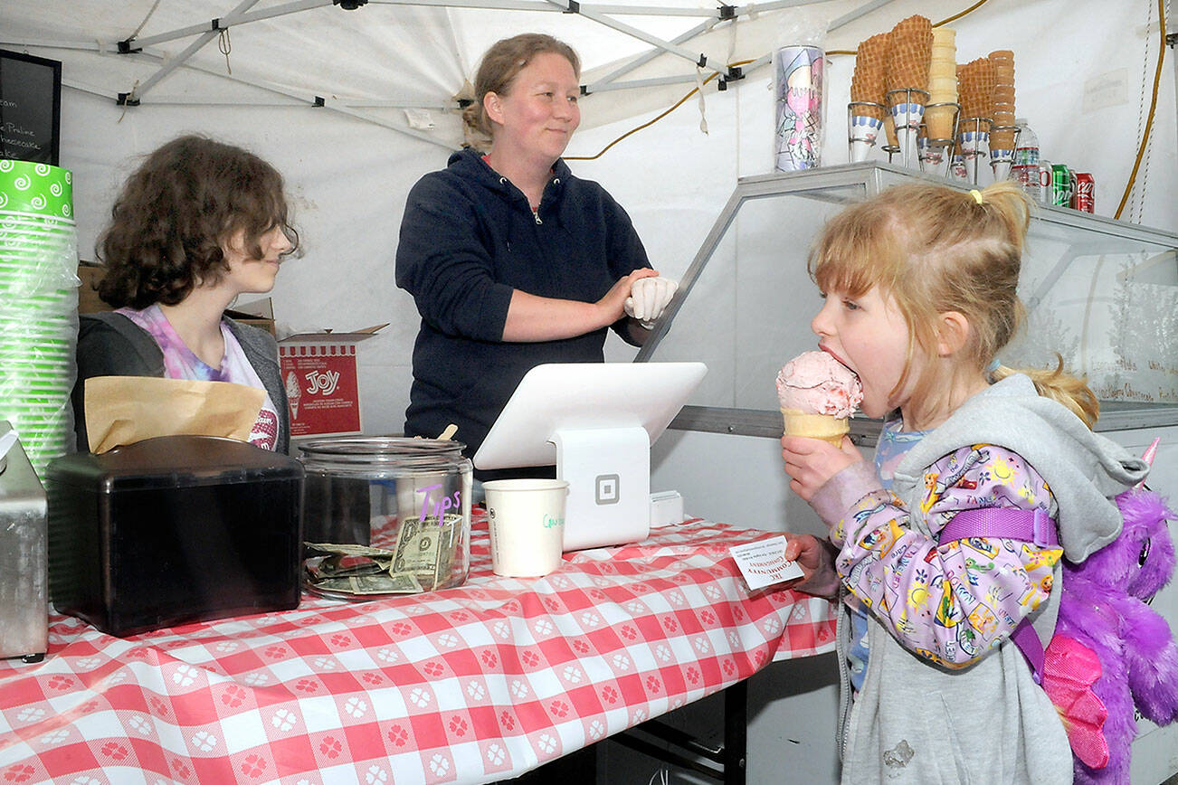 Keith Thorpe/Peninsula Daily News
Alana Black, center, and her daughter, Sophia Strickland, 14, left, operate their Skokomish Valley-based Olympic Mountain Ice Cream tent while 5-year-old Evelyn Bonebreak of Port Angeles enjoys a cone on Friday at the Juan de Fuca Festival of the Arts in Port Angeles.