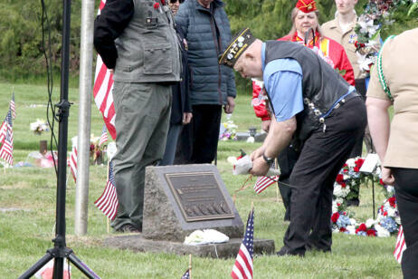 Korean War Veteran Mark Lomax lays flowers on a gravesite during a ceremony Monday at Mt. Angeles Cemetery. He represented one of several branches of the military who laid wreaths in memoriam. (Dave Logan/For Peninsula Daily News)