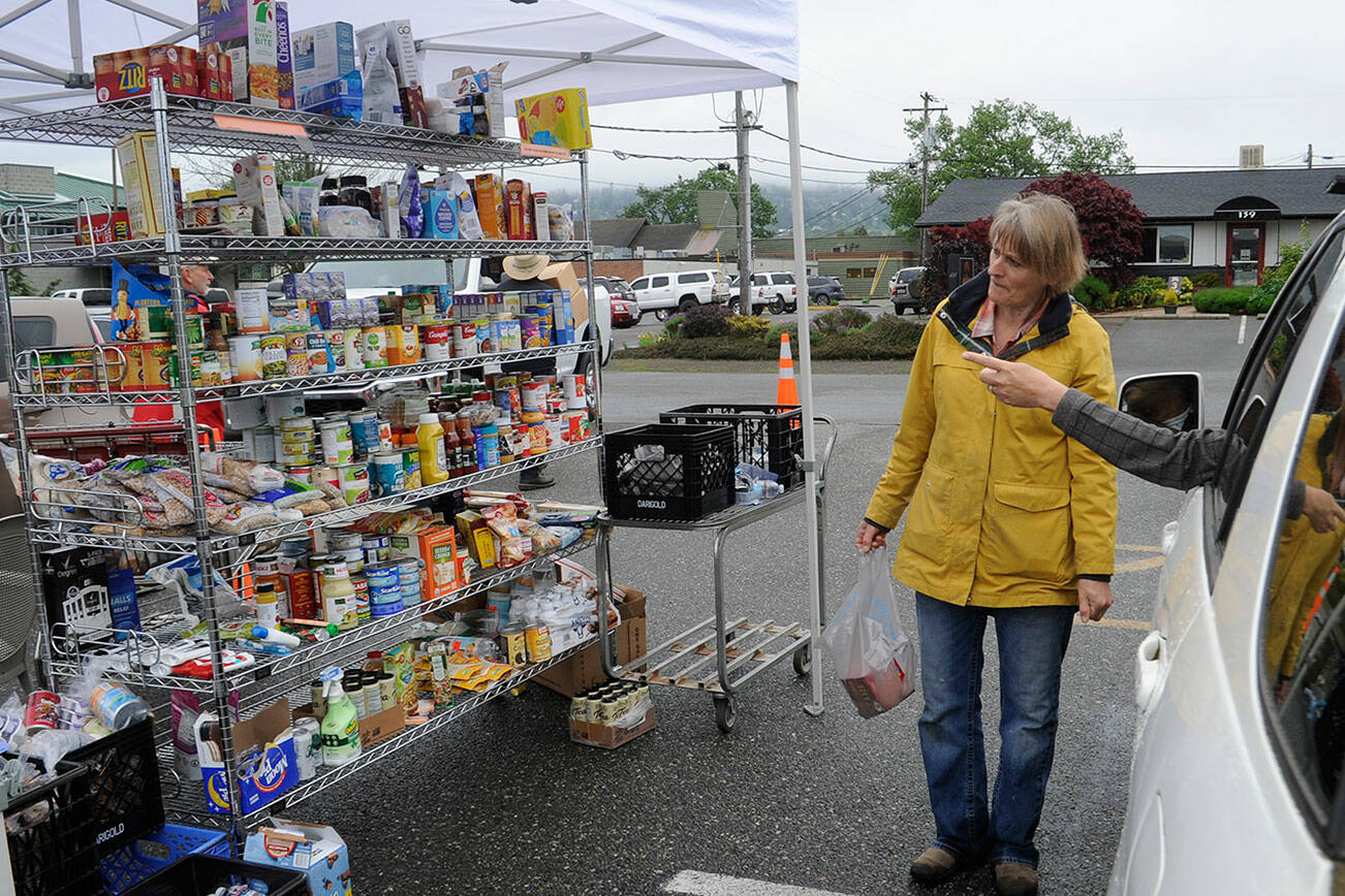 Patti Winnop-Colwell, a longtime Sequim Food Bank volunteer, helps a visitor pick out some items from the facility's drive-through on June 3. (Matthew Nash/Olympic Peninsula News Group)