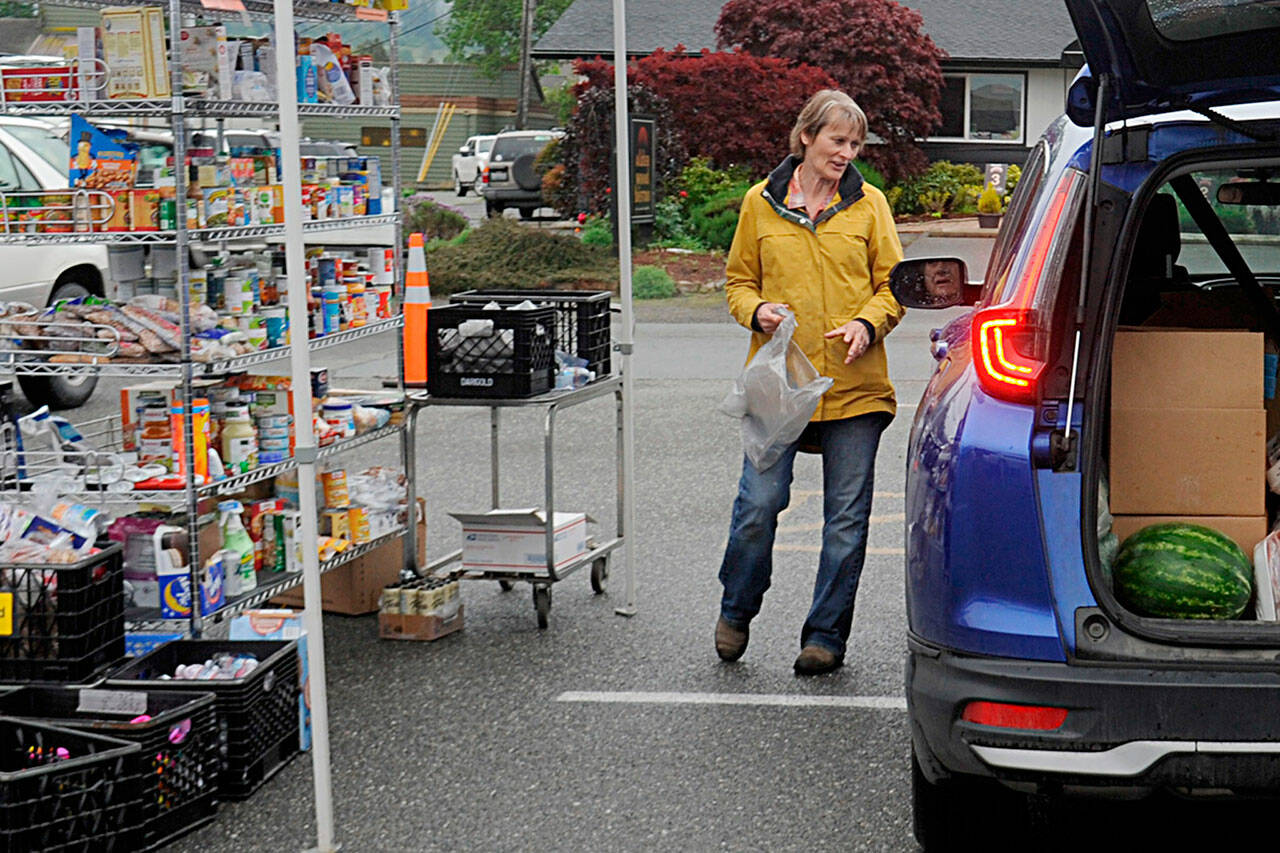 Patti Winnop-Colwell, a longtime Sequim Food Bank volunteer, helps a visitor pick out some items from the facility’s drive-through on June 3. (Matthew Nash/Olympic Peninsula News Group)