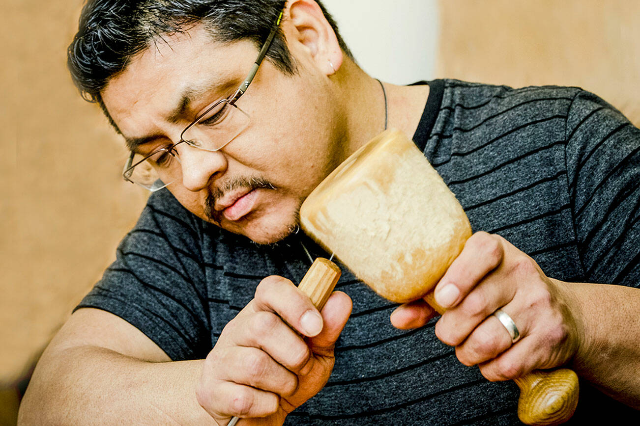 Alex ‘Swiftwater’ McCarty, a Makah artist who will present a lecture, about the Ozette Village, is pictured working on a carving.  (Shauna Bittle)