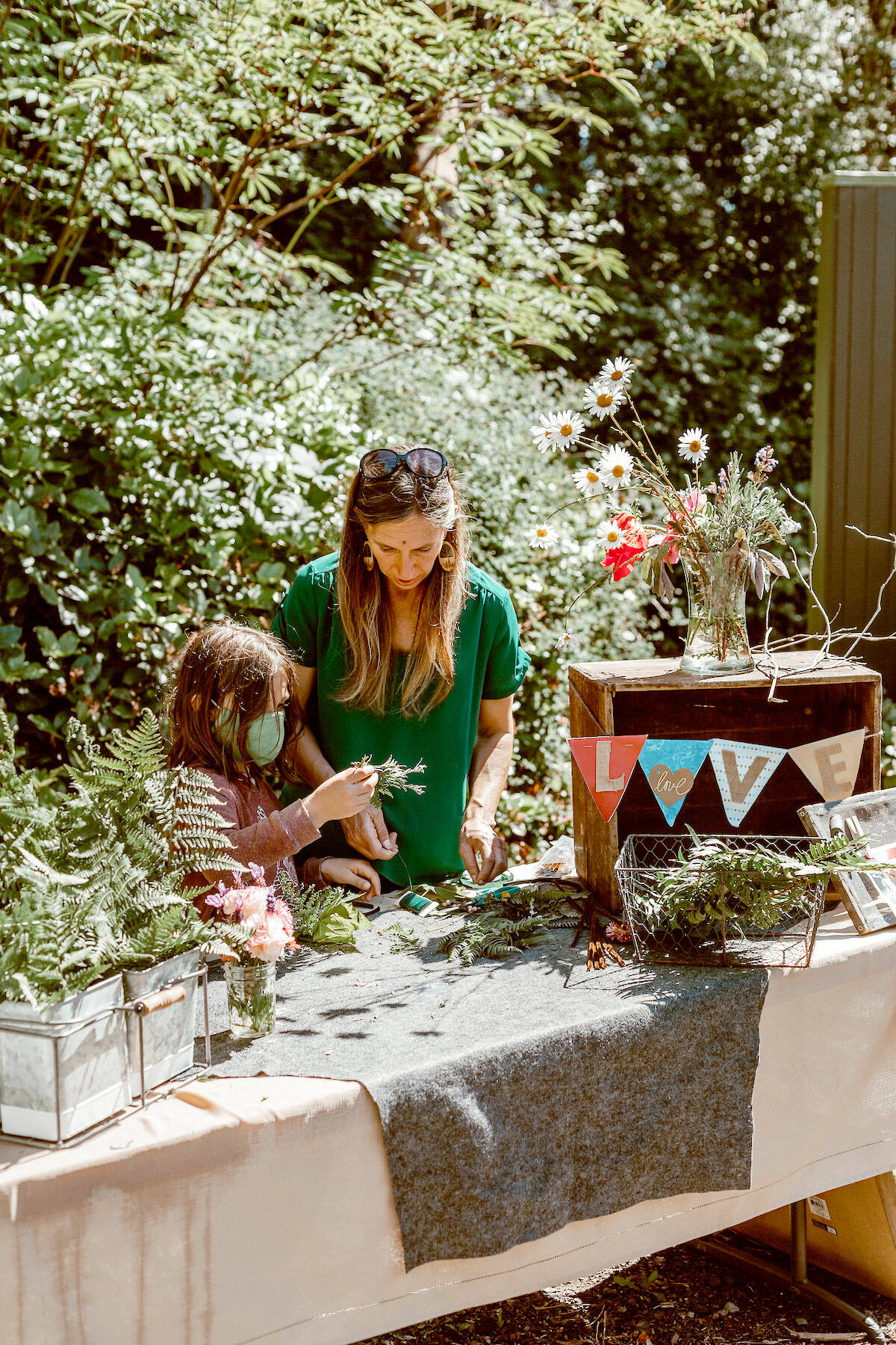 Christine Loewe, executive director of the Port Angeles Fine Arts Center, makes flower crowns with Theo Miller in this file photo. The annual celebration will be on Saturday.