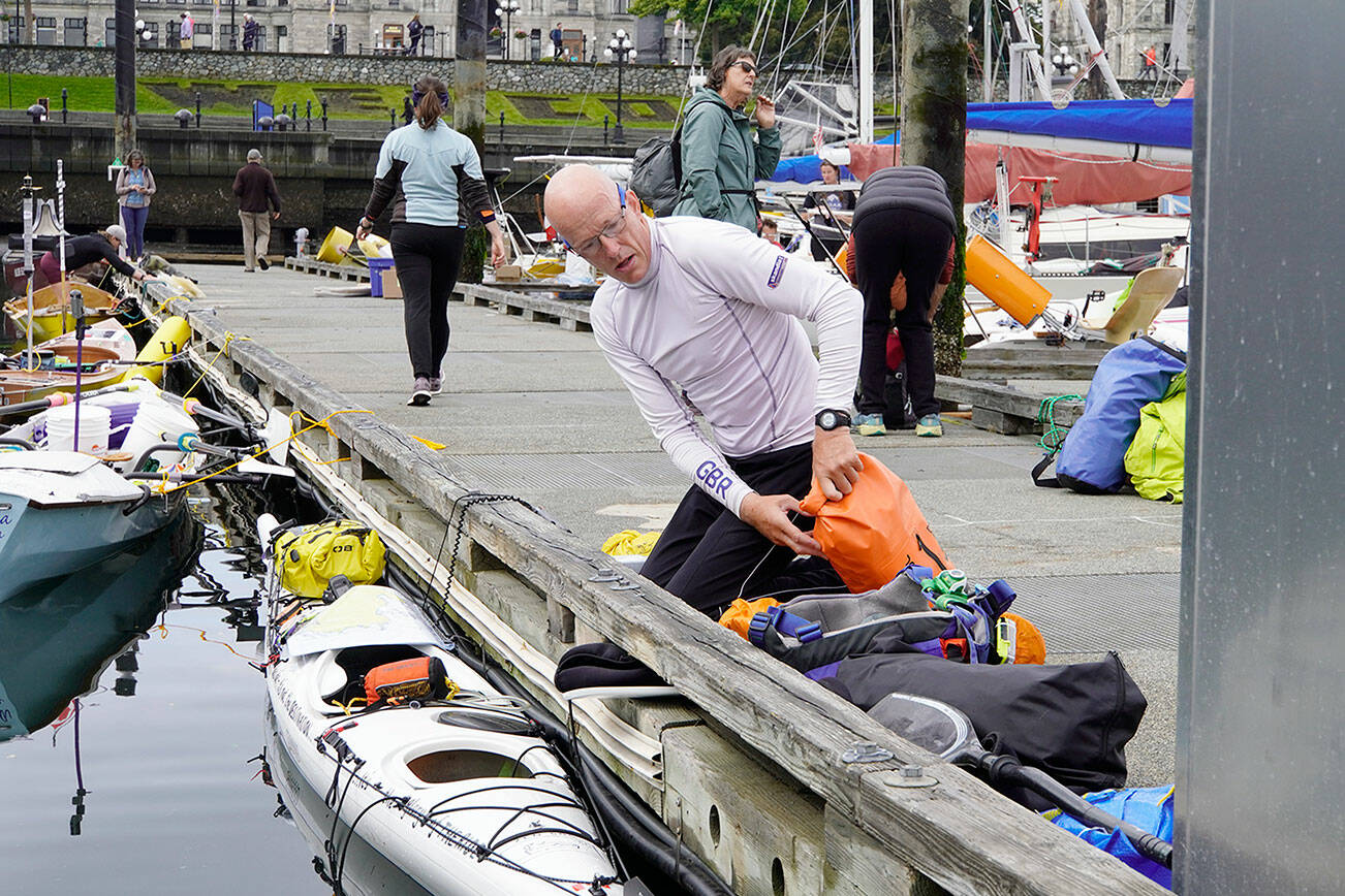 Bob McCall, from Great Britain, loads his kayak with supplies he will need for his 710-mile journey to Ketchikan, Alaska, during the 2022 Race 2 Alaska, which got underway at noon Thursday from Victoria Harbour. A self-described tracker junkie since the first race, McCall decided to enter the race in 2020 and ordered a kayak built in Victoria, but COVID-19 hit and canceled everything. This is the first time he was able to enter and he is looking forward to the adventure. (Steve Mullensky/for Peninsula Daily News)