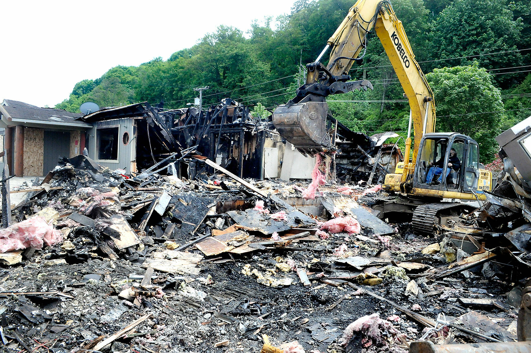 An excavator pulls apart the charred wreckage of the former Castaways Restaurant and Lounge on Thursday in Port Angeles. (Keith Thorpe/Peninsula Daily News)