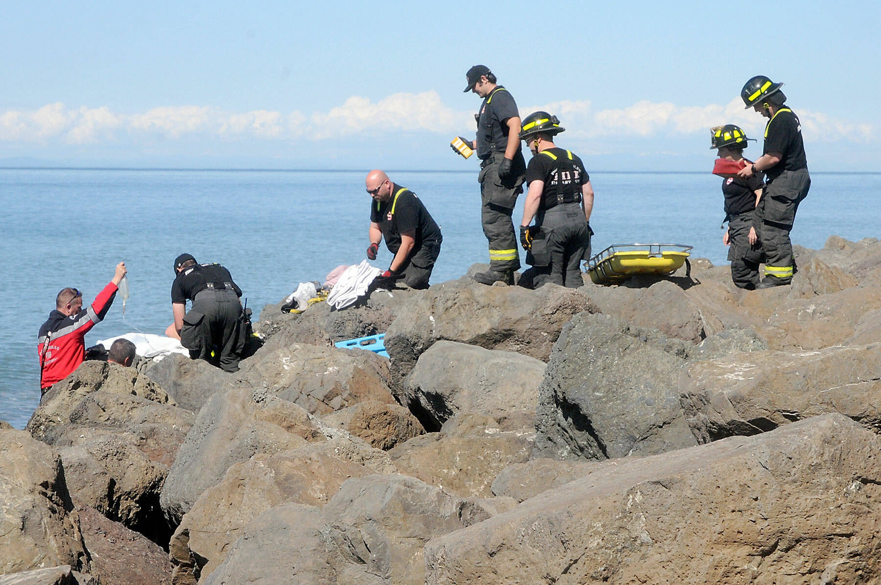 Port Angeles firefighters and paramedics come to the aid of a person who fell from the riprap and became trapped between rocks for three hours on Ediz Hook in Port Angeles on Thursday. (Keith Thorpe/Peninsula Daily News)