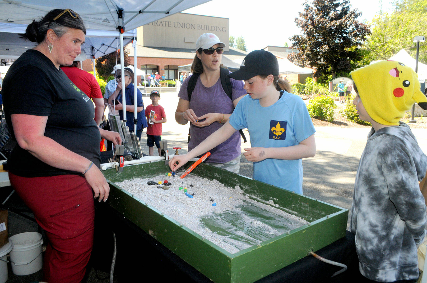 Emily Volz of NatureBridge, left, explains how erosion changes the landscape as members of the Jacobs family of Port Angeles, from left, Monica, Emerson, 11, and Jack, 9, create a miniature flood plain during the Forever StreamFest environmental fair at Peninsula College in Port Angeles. The Saturday event, hosted by the Port Angeles Garden Club, featured a variety of displays and educational activities, along with music and guest speakers, geared toward protection of the air, water, forests, land and wildlife. (Keith Thorpe/Peninsula Daily News)