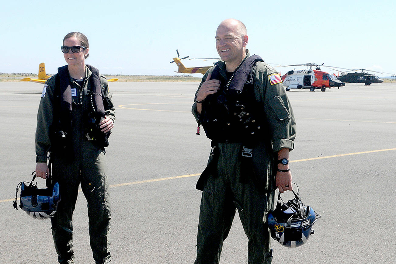 Cmdr. Joan Snaith, outgoing commanding officer of U.S. Coast Guard Air Station/Sector Field Office Port Angeles, left, and incoming officer Cmdr. Brent Schmadeke stand on the tarmac after Thursday’s unconventional change of command ceremony that took place during a helicopter flyby at the base. (Keith Thorpe/Peninsula Daily News)