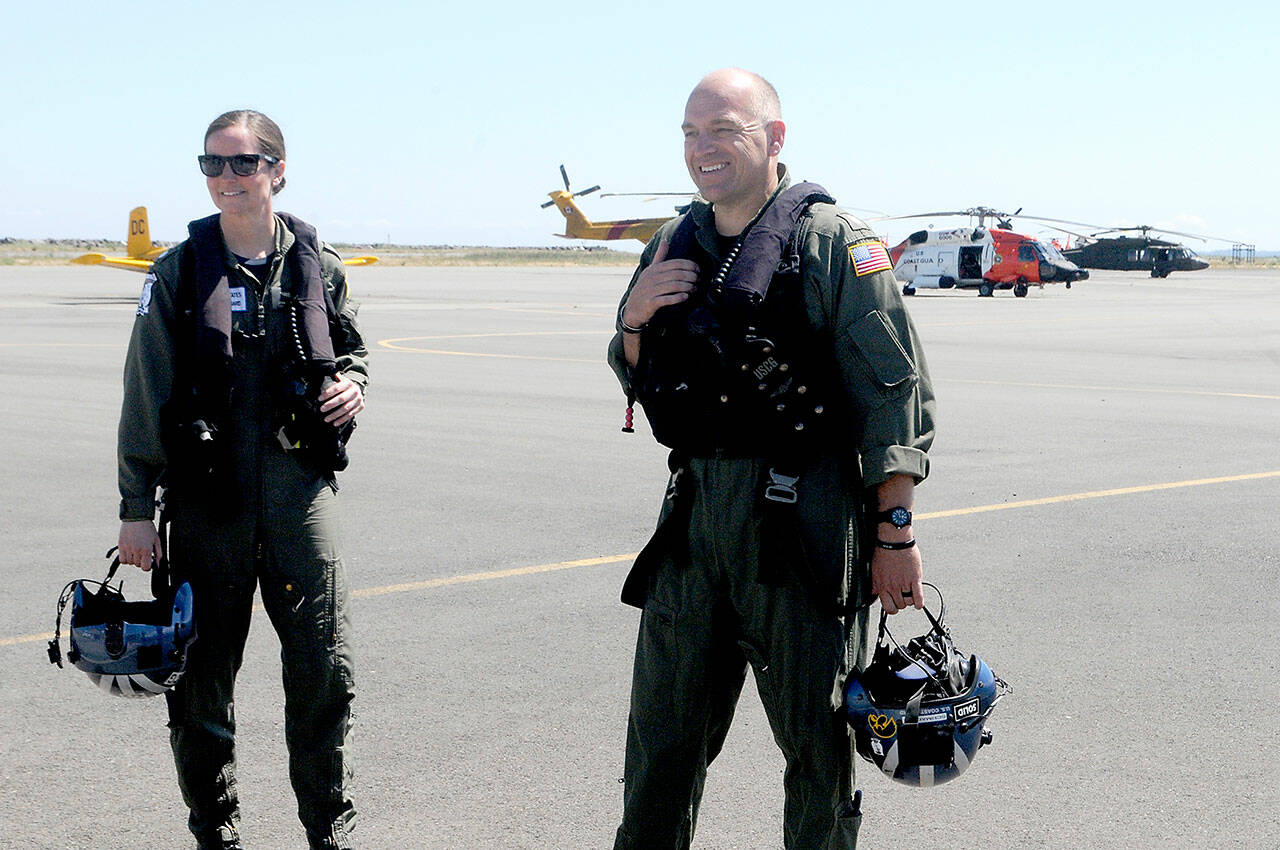 Cmdr. Joan Snaith, outgoing commanding officer of U.S. Coast Guard Air Station/Sector Field Office Port Angeles, left, and incoming officer Cmdr. Brent Schmadeke stand on the tarmac after Thursday’s unconventional change of command ceremony that took place during a helicopter flyby at the base. (Keith Thorpe/Peninsula Daily News)