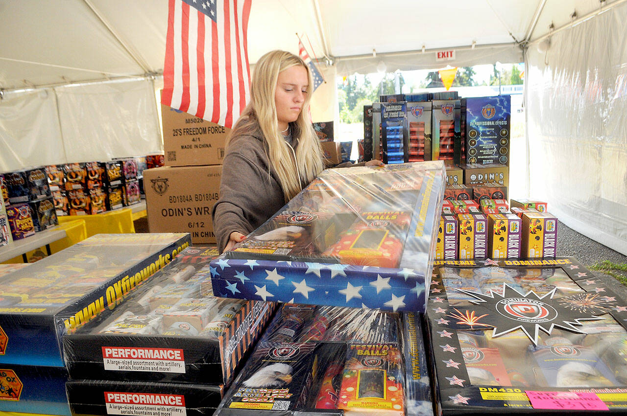 Kira Watson replenishes inventory at the Olympic Fireworks stand at U.S. Highway 101 and Gales Street on the east side of Port Angeles on Thursday. (Keith Thorpe/Peninsula Daily News)