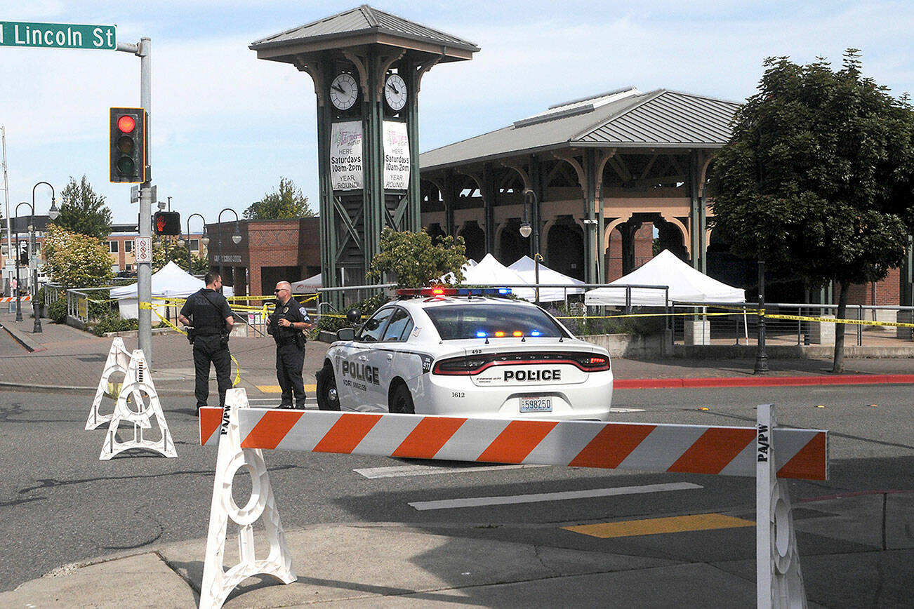 Keith Thorpe/Peninsula Daily News

Port Angeles Police Detective Trevor Dropp, left, and Sgt. Kevin Miller keep watch at The Gateway in downtown Port Angeles after a suspicious package was found at the Port Angeles Farmers Market on Saturday morning. The market was evacuated and the 200 block of North Lincoln Street was barricaded until a Washington State Patrol bomb squad arrived from Bremerton early Saturday afternoon.