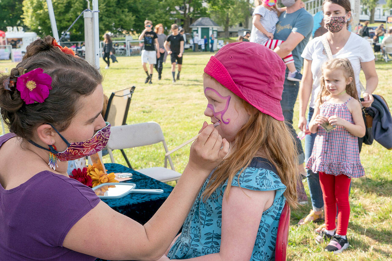 The Field Day event at Fort Worden State Park had something for everyone, including Port Townsend’s Rosie Dunham, 6, who is getting her face painted by artist Alexa Rose. Other activities Saturday included tug-o-war, music, bouncy houses and delicious foods. (Steve Mullensky/for Peninsula Daily News)