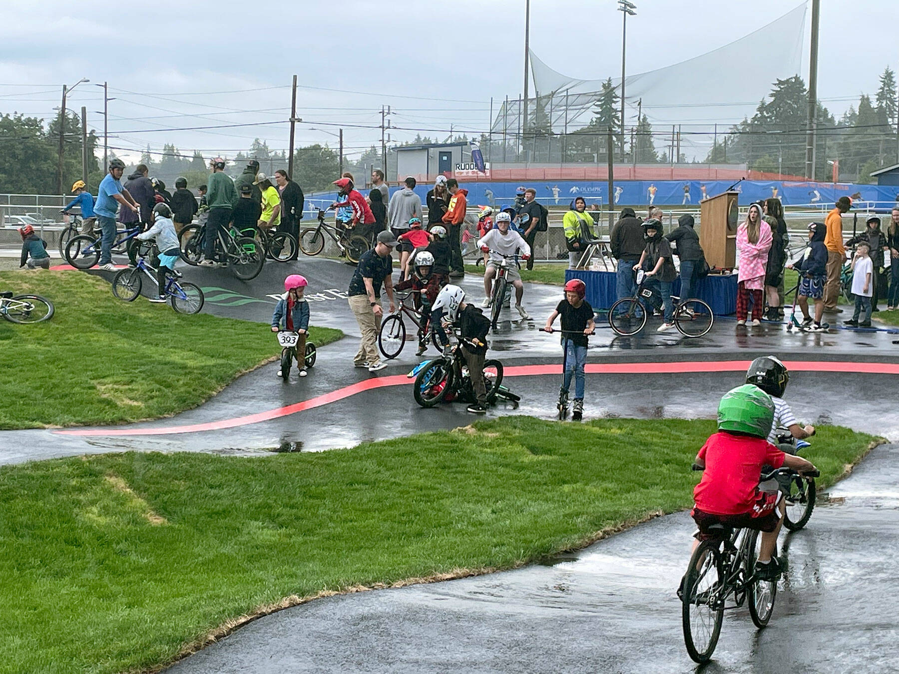 Kids on BMX bikes, mountain bikes, skateboards and scooters waited patiently through a grand opening ceremony of ribbon-cutting, remarks and recognitions, so they were more than ready to try out the new pump track Wednesday at Erickson Playfield. First announced three years ago, the 14,442-square-foot pump track is the largest in the Pacific Northwest built by Velosolutions and it’s the first adaptive track in the country. Port Angeles Parks & Recreation and Lincoln Park BMX Association led the project, which will provide a free, safe and all-ages recreational outlet located in the center of the city. (Paula Hunt/Peninsula Daily News)