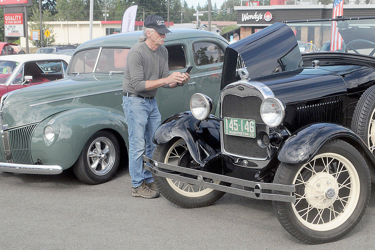 David Johannessohn of Sequim takes a photograph of the motor of a 1929 Ford Model A on Saturday at the 26th annual Ruddell Cruise-In car show at Ruddell Auto in Port Angeles. The event featured more than 200 vintage and classic automobiles and trucks in an evening that included food, live music and a dunk tank. (Keith Thorpe/Peninsula Daily News)