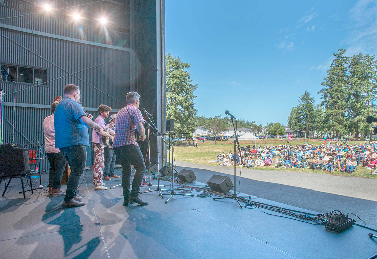 A group of musicians, led by Brandon Godman, in blue shirt, who had never played together before, perform a rousing a set of Bluegrass music to an audience on Littlefield Green at Fort Worden State Park on Saturday. Centrum’s weeklong Fiddle Tunes Festival ended with this finale concert under the sun. (Steve Mullensky/for Peninsula Daily News)