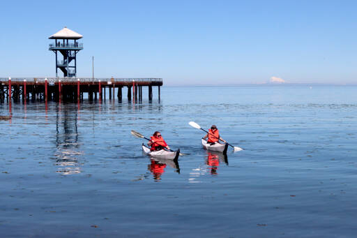 Amelia Kalagher of Port Angeles, left, and Jaedy Lee of Boston kayak near City Pier in Port Angeles on a clear day with Mount Baker off in the distance. Temperatures are forecast for the mid- to upper 60s for the rest of the week, with clouds moving in by Friday. (Dave Logan/for Peninsula Daily News)