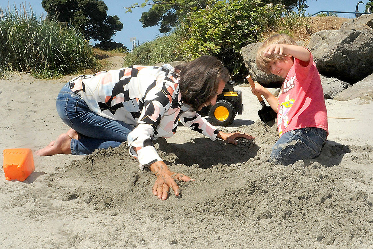 Keith Thorpe/Peninsula Daily News
Five-year-old Barron Strangle, right, reacts as his grandmother, Ellen Mack, buries him thigh-deep in a hole they excavated at Hollywood Beach in Port Angeles on Tuesday. The pair, both from Port Angeles, were taking advantage of a sunny summer day on the sand.