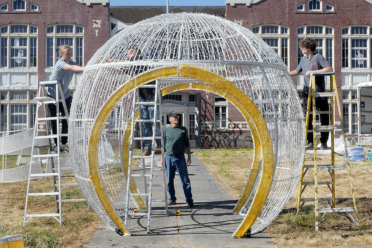 Keith Thorpe/Peninsula Daily News
Rick Smith of the Olympic Medical Center Foundation, center, watches as Aidan Butterworth, left, Dave Jungck of Kent-based AV Factory, on ladder in middle, and Tanner McLean do a test assembly of a giant Christmas decoration on Wednesday on the front lawn of the old Lincoln School in Port Angeles. The decoration, donated by the Microsoft Corporation, will become part of a display in the foundation's Festival of Trees in November, and then be incorporated into the Port Angeles Winter Ice Village in December.