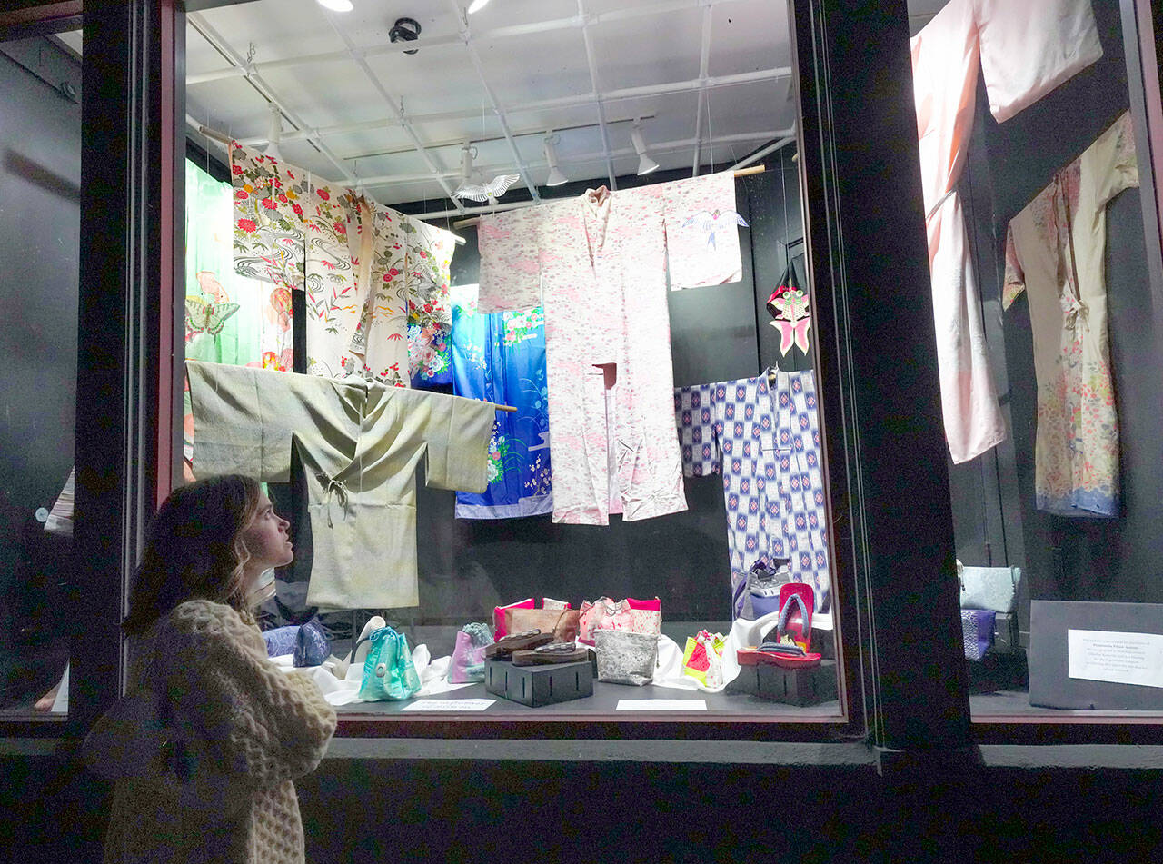 Abbey Engrav, visiting Port Townsend from New York City for her brother’s wedding on Saturday, looks at the vintage Japanese garments and shoes on display at the Peninsula Fiber Artists display window on Tyler Street in the Uptown Neighborhood on Friday night. (Steve Mullensky/for Peninsula Daily News)