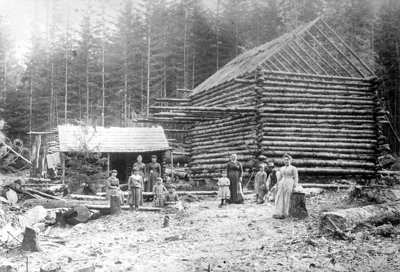 North Olympic History Center
A two story log cabin being built. One man, four women and five children (Unidentified) are shown. A smaller log cabin is beside the cabin under construction.