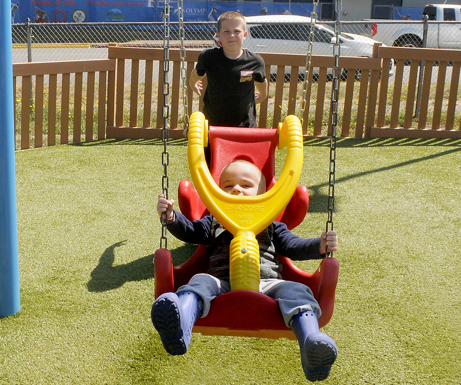 Liam Owens of Sequim, 11, pushes his brother, Kamden Owens, 2 1/2, on a swing at the Dream Playground at Erickson Playfield in Port Angeles. The pair were among dozens of children taking advantage of the year-old volunteer-built playground. (Keith Thorpe/Peninsula Daily News)