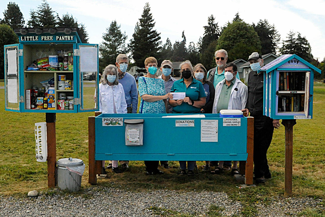 Agnew Little Free Pantry volunteers greet Sarah Irish, a Molina Healthcare community engagement specialist, fifth from left, as she donates $2,000 for food from the agency. Some of the volunteers who work daily to restock the pantry, include, from left, Susan Harris, Dave Large, Florence and Michael Bucierka, Irish, Peggy and John Toppenberg, Dave Iezzi and Ren Garypie. (Matthew Nash /Olympic Peninsula News Group)