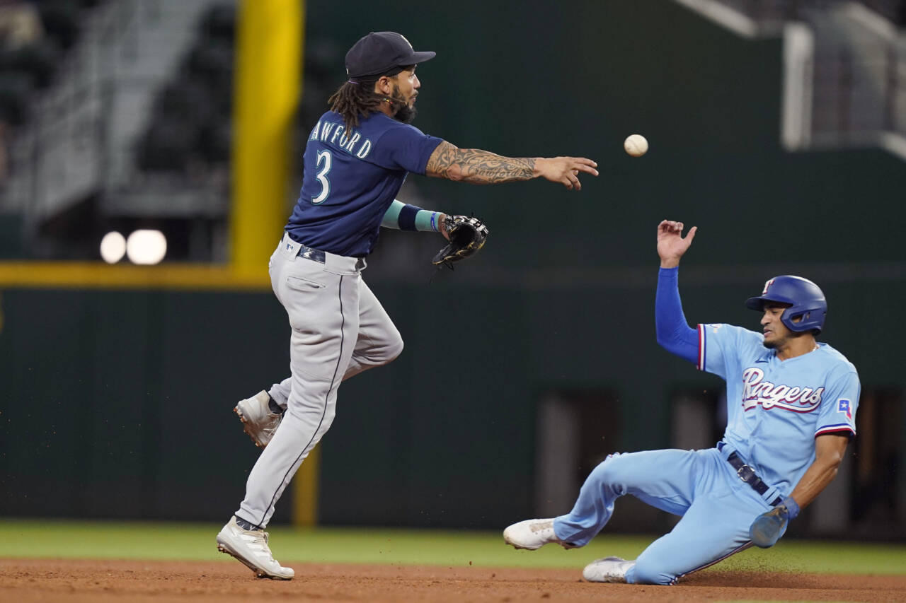 Seattle Mariners shortstop J.P. Crawford (3) throws from second base to turn a double play as Texas Rangers’ Bubba Thompson, right, slides in during the fourth inning of a baseball game in Arlington, Texas, Sunday, Aug. 14, 2022. Rangers’ Josh Smith was out at first base. (AP Photo/LM Otero)
