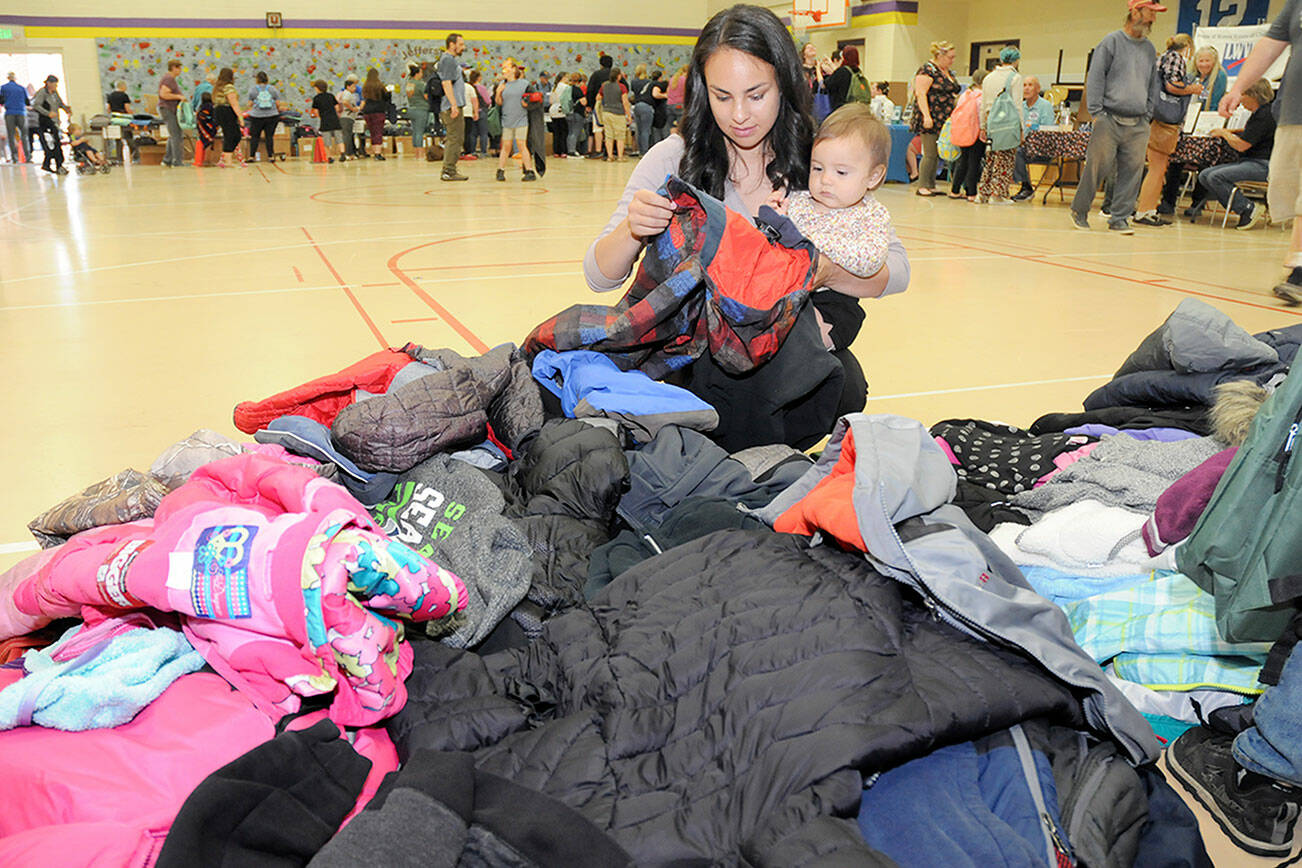 Heidi Eberle of Port Angeles and her daughter, Akira Abbitt, 11 months, sort through a stack of free children’s coats during Saturday’s Port Angeles School District Back to School Fair at Jefferson Elementary School. (Keith Thorpe/Peninsula Daily News)