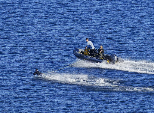 A belly board rider gets a slingshot boost and zooms almost ahead of the tow boat as they zip over the cooling waters of Port Townsend Bay. High temperatures are expected to remain in the 70s through Labor Day weekend. (Steve Mullensky/for Peninsula Daily News)