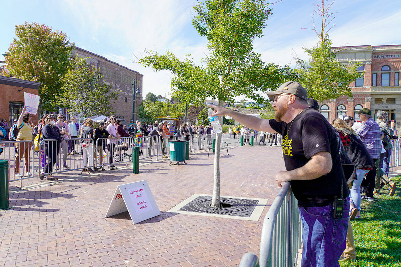 Erik Rohde from Whidbey Island, a member of the Washington Three Percenters with other protesters, trades barbs with counter protesters over a buffer zone created by the Port Townsend police to control possible violence between the two factions during a rally at Pope Marine Park in Port Townsend on Saturday. (Steve Mullensky/for Peninsula Daily News)