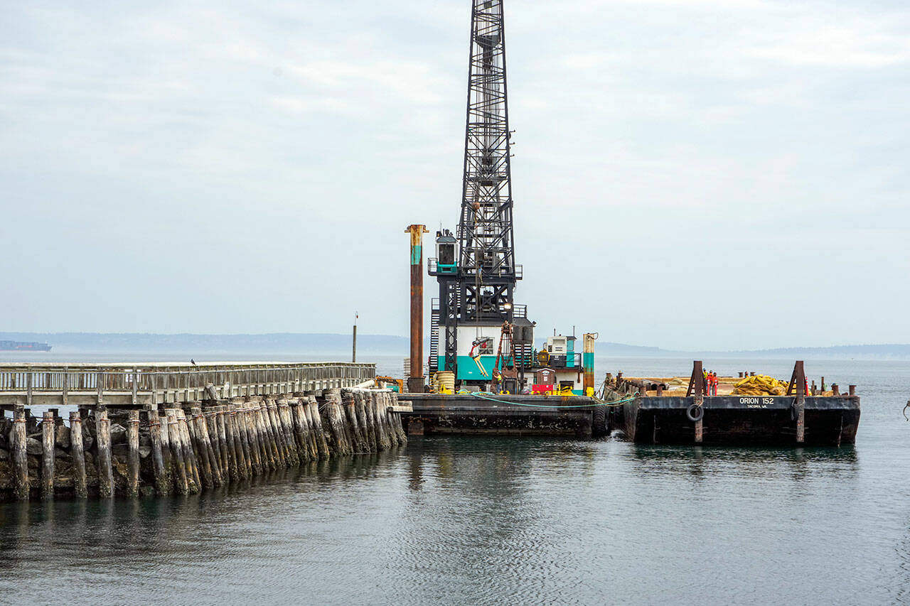 Workers prepare oil and containment boom lines on Tuesday for placing around the creosote pilings that will be removed when construction of the new entrance to Point Hudson Marina begins on Thursday. The booms will contain and extract any oil residue that might leak from the pilings. A groundbreaking ceremony is set today. (Steve Mullensky/for Peninsula Daily News)