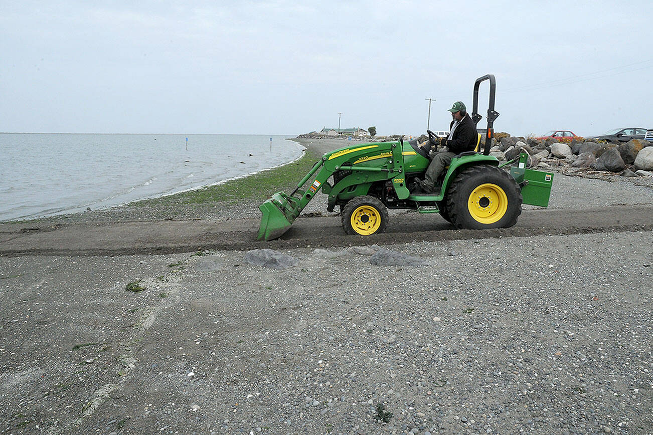 Ralph Parsons of Port Angeles, an employe of the Clallam County Parks, Fair and Facilities department, scrapes sand and gravel from the public boat launch at Cline Spit County Park. Parsons said readying the ramp is part of an effort to facilitate boaters and anglers during fishing season. (Keith Thorpe/Peninsula Daily News)
