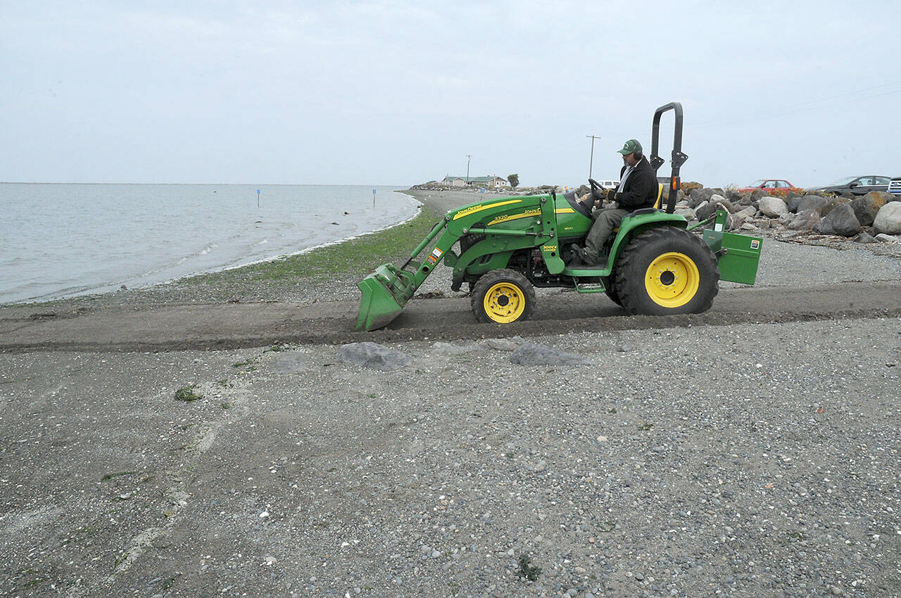 Ralph Parsons of Port Angeles, an employe of the Clallam County Parks, Fair and Facilities department, scrapes sand and gravel from the public boat launch at Cline Spit County Park. Parsons said readying the ramp is part of an effort to facilitate boaters and anglers during fishing season. (Keith Thorpe/Peninsula Daily News)