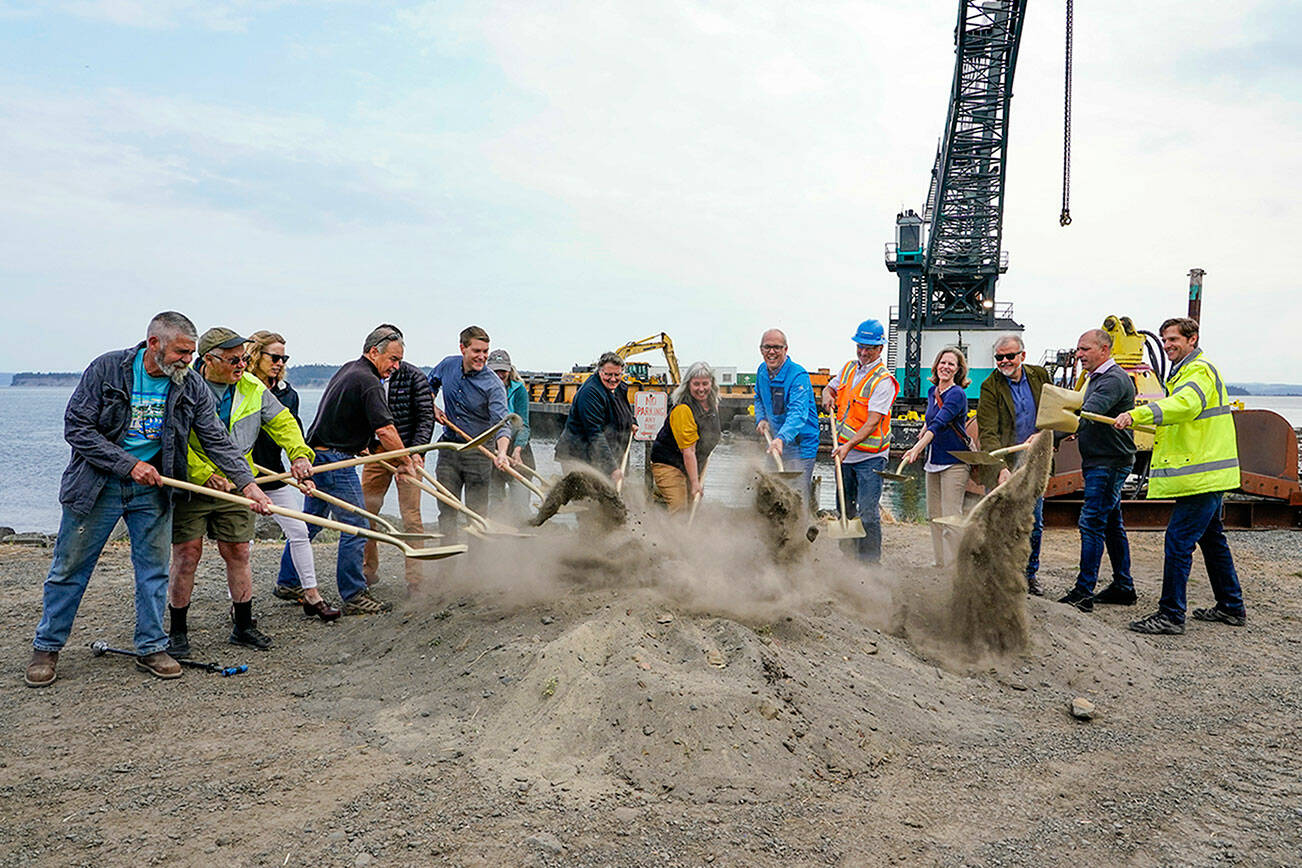 Port Townsend Mayor David Faber, sixth from the left, and other council members and port commissioners toss a ceremonial golden shovel of dirt to break ground on the Point Hudson jetty replacement project on Wednesday at the northern breakwater of the Point Hudson Marina. The marina will reopen in March 2023. After next year’s Wooden Boat Festival, the south breakwater will receive the same treatment. (Steve Mullensky/for Peninsula Daily News)