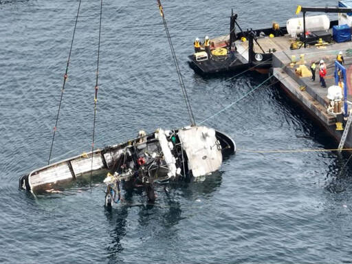 The Aleutian Isle lays on its side suspended by crane after being lifted to the surface on Saturday. (Canada Dept. of Fisheries and Oceans)