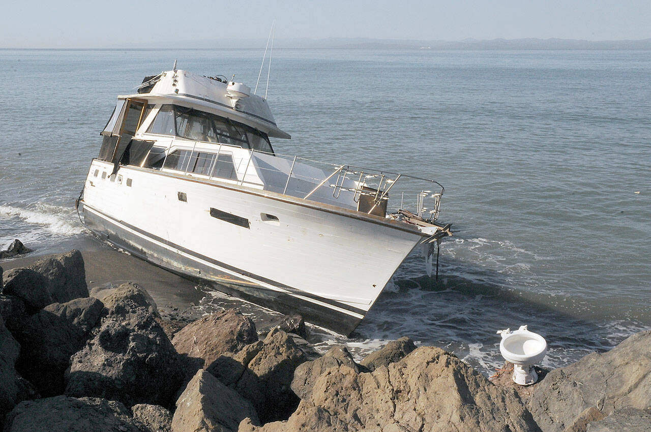 The cabin cruiser Eudora sits grounded on the north side of Ediz Hook in Port Angeles on Tuesday as a toilet, which may have been aboard the vessel, sits on the rocks above the high tide line. (Keith Thorpe/Peninsula Daily News)
