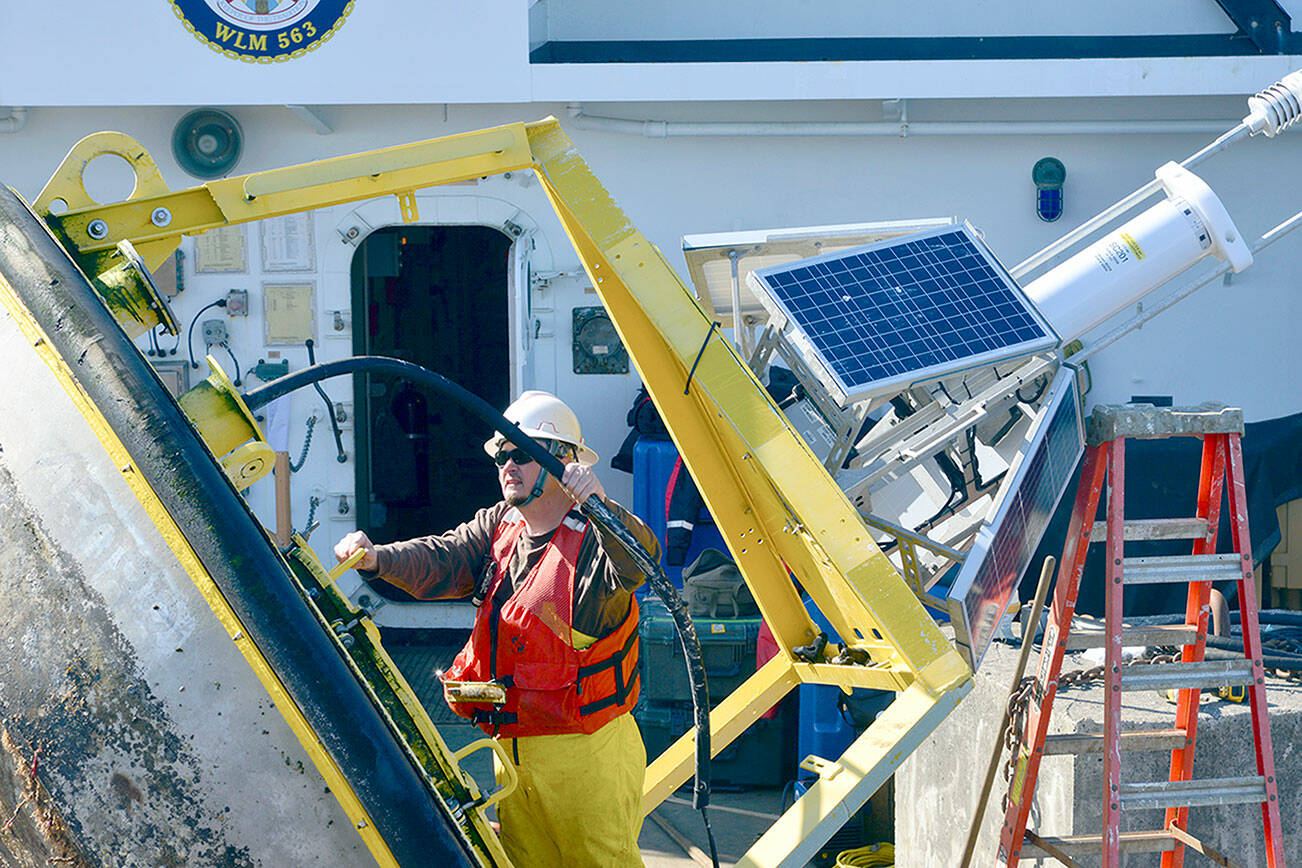 A technician works on the monitoring equipment housed on the buoy onboard the U.S. Coast Guard Cutter Henry Blake in the Strait of Juan de Fuca on Sept. 20. The buoy, part of the National Oceanic and Atmospheric Administration’s network of weather monitoring stations, stopped transmitting weather data last year. Technicians replaced the monitoring equipment last week. (Peter Segall / Peninsula Daily News)