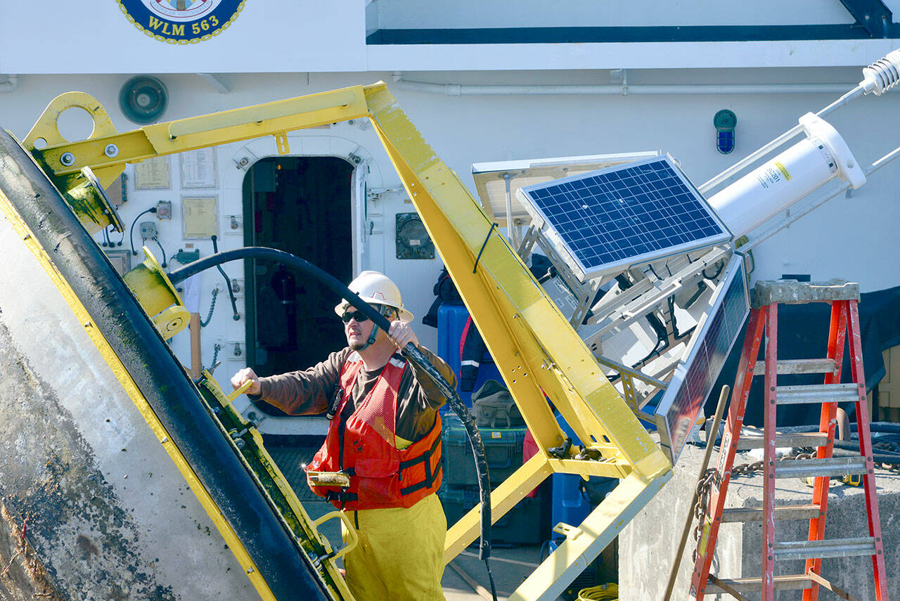 A technician works on the monitoring equipment housed on the buoy onboard the U.S. Coast Guard Cutter Henry Blake in the Strait of Juan de Fuca on Sept. 20. The buoy, part of the National Oceanic and Atmospheric Administration’s network of weather monitoring stations, stopped transmitting weather data last year. Technicians replaced the monitoring equipment last week. (Peter Segall / Peninsula Daily News)
