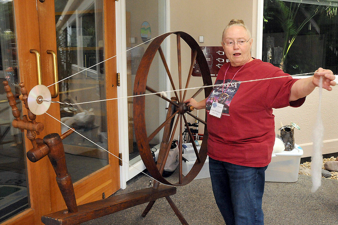Rocky Wisniewski of Sequim, a member of the North Olympic Shuttle Spindle Guild, demonstrates how to spin fiber on a walking wheel during Saturday’s Pacific Northwest Fiber Exposition at Vern Burton Community Center in Port Angeles. The two-day event featured a wide variety of demonstrations, exhibits, workshops and a marketplace showcasing all things fiber. (Keith Thorpe/Peninsula Daily News)